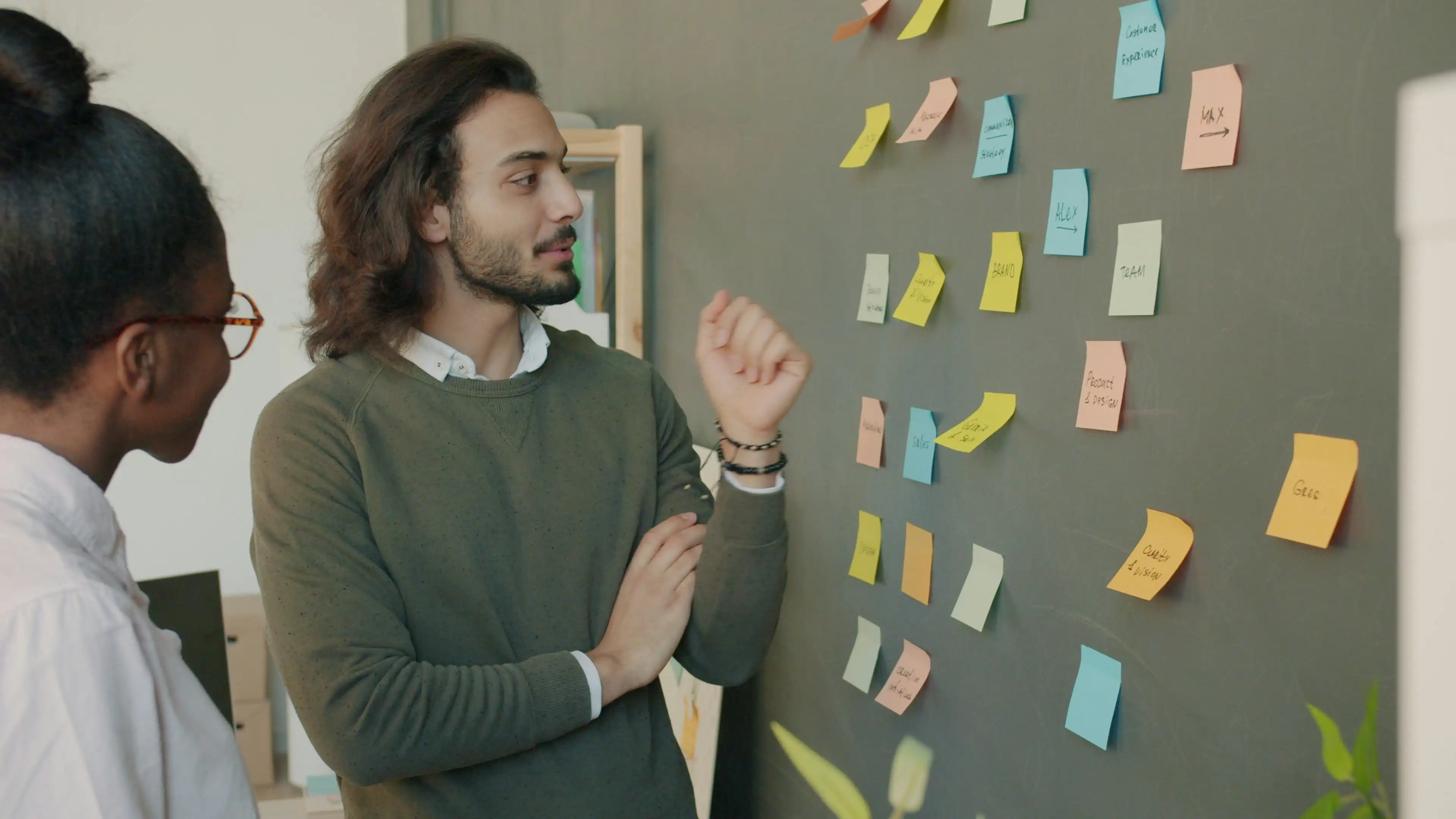 Mitarbeiter diskutieren über Post-Its an Wand